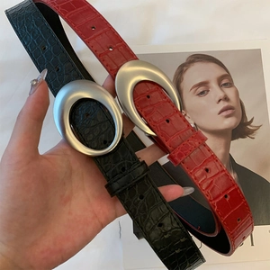 Détail de ceintures en cuir gaufré crocodile noir et rouge avec boucles ovales en argent mat