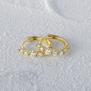 Macro detail of gold S925 silver hoop earrings with five sparkling inlaid gemstones
