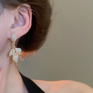 Macro shot of gold leaf tassel earrings with sparkling cubic zirconia on a female model