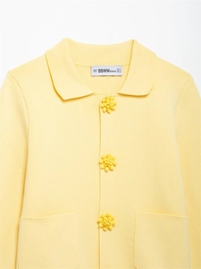Detail of yellow knit cardigan showing collar, flower buttons, and ribbed texture