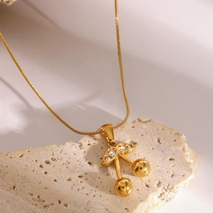Dettaglio di una collana con ciondolo a ciliegia dorata e cristalli su pietra