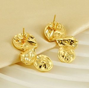 Detailansicht der goldenen Ohrringe mit Hammerschlag-Textur auf Seide mit flüssigem Design