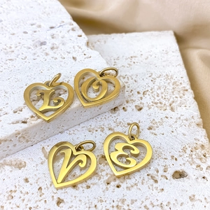 Close-up of gold stainless steel heart pendants with LOVE letters on white stone