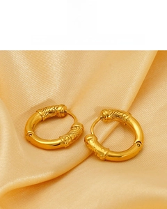 Gros plan de boucles d'oreilles créoles plaquées or 18K avec motifs gravés traditionnels