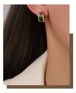 Detail of vintage gold C-shape earrings with deep green enamel on model ear