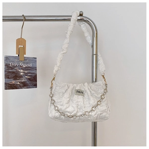 Detail of white pleated shoulder bag with silver floral chain and brand label