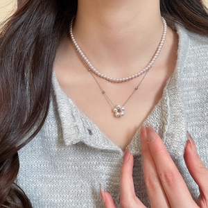 Detail of layered pearl necklace with floral pendant on elegant neck collarbone