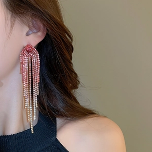 Macro shot of long geometric tassel earrings with pink and gold rhinestones on model
