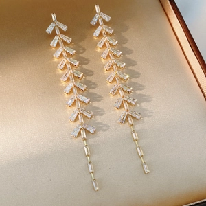 Macro view of gold tassel earrings with zircon leaf clusters on satin lining