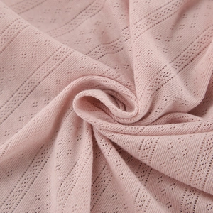 Detail of light pink pointelle knit fabric showing soft texture and diamond pattern