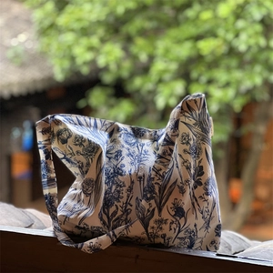 Close-up of botanical tie-dye canvas tote bag with blue floral print on wooden fence