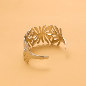 Detail showing an open cuff silver metal bracelet with a vintage hollow leaf design