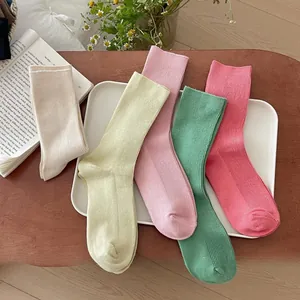 Close-up of ribbed cotton crew socks in pastel colors displayed in a rustic home setting