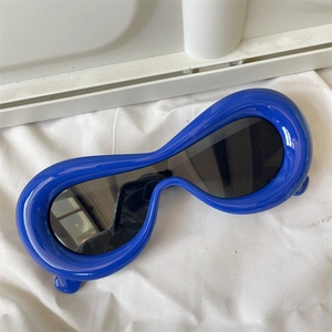 Detail view of bold blue polygonal frames with black lenses on a white minimalist texture