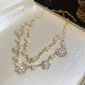 Macro view of double-layer gold necklace featuring diamond-encrusted floral pearl pendant