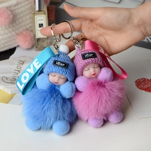 Sleeping baby plush keychain with fox fur pompom and knitted hat in blue and pink tones