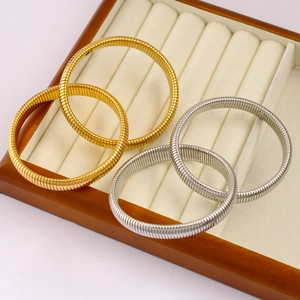 Detailed view of gold and silver Tubogas stretch bracelets on a jewelry display tray