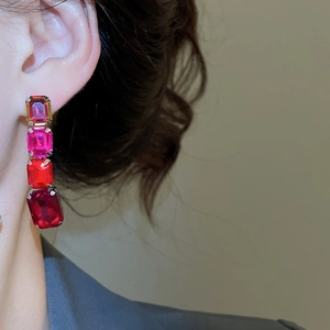 Detailed close-up of long earrings with rectangular orange and red gradient gemstones