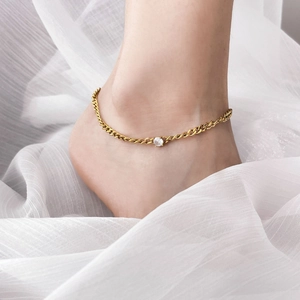 Gold anklet with hollow chain and square cubic zirconia on a model's ankle