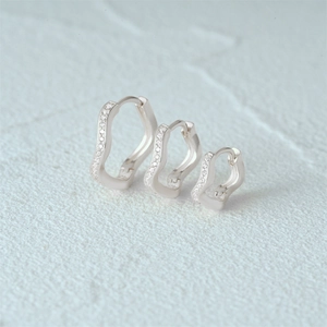 Detail of silver S925 earrings set with irregular wave rings and sparkling zircon stones
