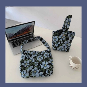 Detail view of jacquard floral shoulder bag and bucket bag set on a white desk