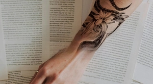 Detailed view of snake and lily temporary tattoo on arm with a vintage book background