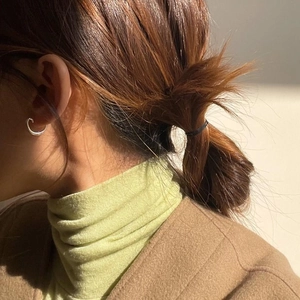 Close-up of minimalist silver hoop earrings on model with warm sunlight reflection