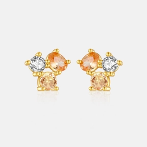 Macro shot of gold S925 sterling silver studs with three-tone zircon stones and reflection