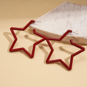 Macro view of dark red acrylic star earrings with smooth finish on a stone base