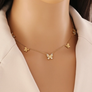 Détail du collier papillon doré avec breloques dépolies et pendentif en nacre blanche
