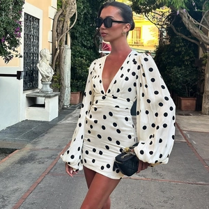 Dettaglio dell'abito a pois con maniche lunghe a campana e profondo scollo a V sexy