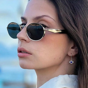 Primer plano de gafas de sol redondas doradas y pendientes de ojo de la suerte