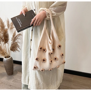 Close-up of beige knitted tote bag featuring 3D brown floral appliqués and soft texture