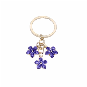 Cute golden keychain with three purple enamel flower pendants on a white background