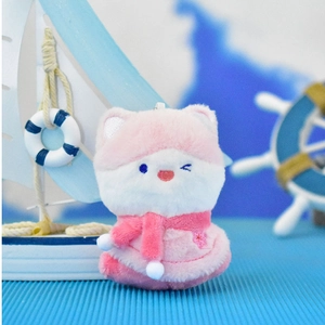 Detail of a cute pink plush fox keychain featuring a scarf and embroidered wink.