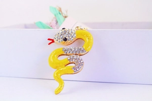 Detailed close-up of a golden snake keychain with yellow enamel and sparkling rhinestones