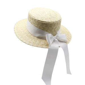Gros plan d'un chapeau de paille orné d'un large ruban en soie blanche et nœud
