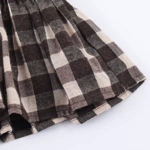 Macro detail of honeycomb plaid fabric showing stitching and texture on pleated hemline