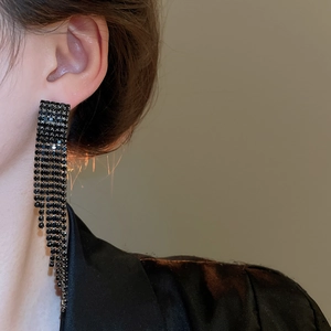 Gros plan de boucles d'oreilles élégantes à pompons en strass noirs sur un modèle