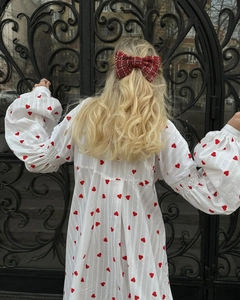 Détail du nœud rouge en tweed et robe blanche à imprimé cœur avec manches bouffantes