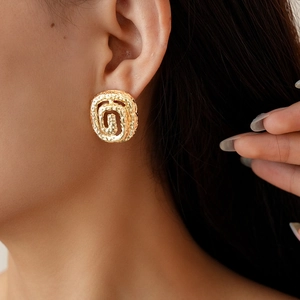 Detailed view of a golden twisted spiral earring with hammered texture on a model