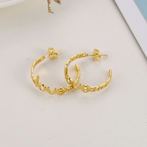 Detail view of 18K gold plated LOVE letter hoop earrings with a polished finish