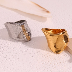 Close-up of gold and silver irregular geometric rings with water droplets on white surface
