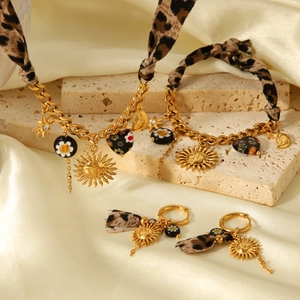 Detail of celestial gold jewelry set with leopard print fabric on a textured stone