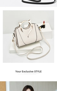 Detail showing the cream handbag's unique cat-shaped gold metal handle and shoulder strap