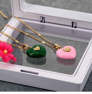 Detail of pink and green heart pendant necklaces with gold chains in a white gift box