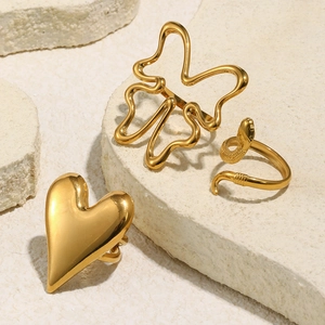 Detailed close-up of 18K gold plated butterfly, snake, and heart rings on natural stone