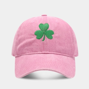 Detailed close-up of green clover embroidery on a vintage pink washed cotton baseball cap