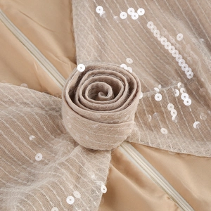 Close-up of champagne gold sequins, mesh fabric, 3D floral accents, and smooth zipper detail
