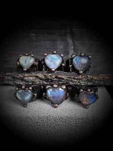 Macro detail of six handmade labradorite heart rings with dark bronze vintage plating